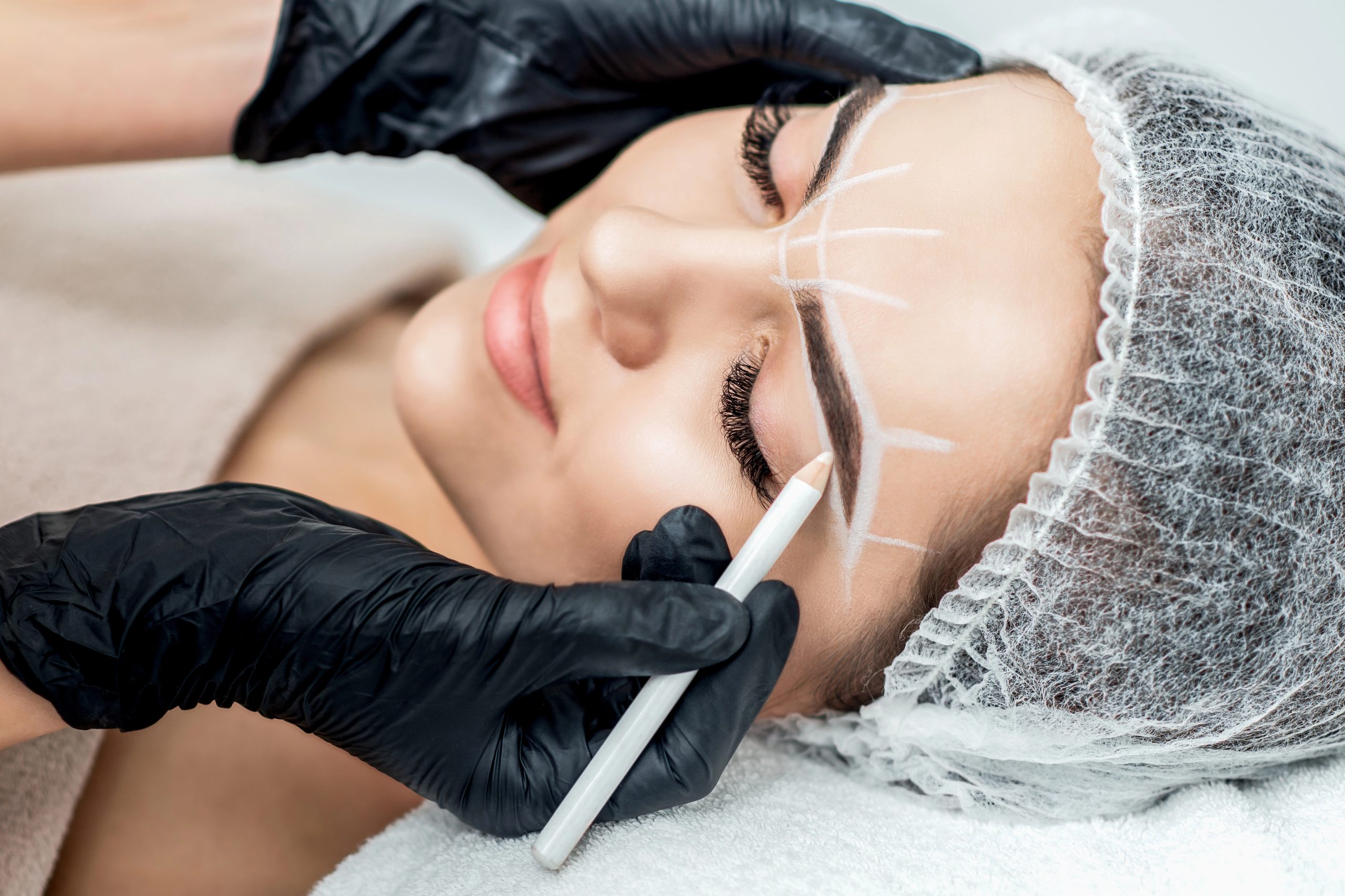 manos de mujer en estética marcando ineas de cejas